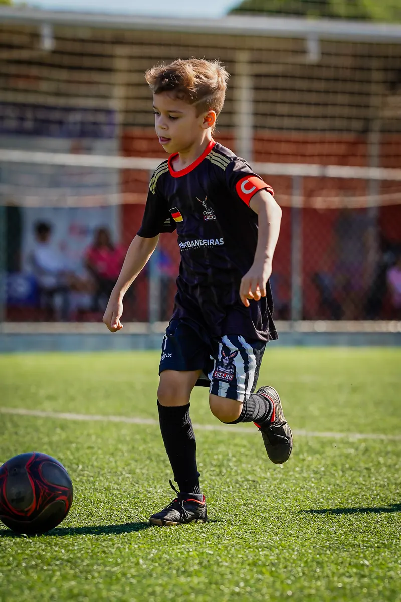 Aluno conduzindo a bola no campo de grama